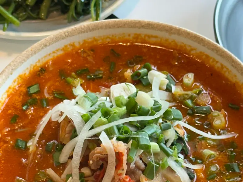 매운 차돌 쌀국수의 클로즈업 사진. 붉은 국물과 차돌박이, 파가 인상적이다.