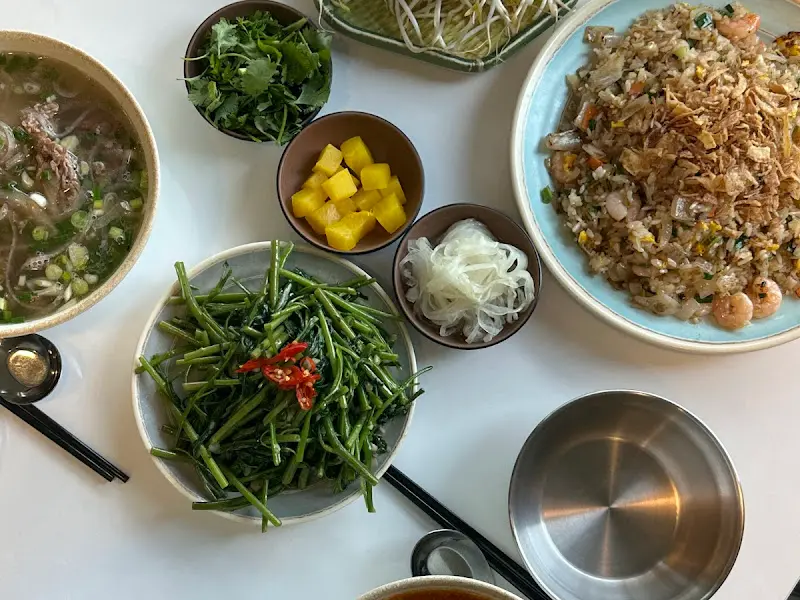 테이블 위에 놓인 다양한 음식들. 쌀국수, 볶음밥, 모닝글로리 볶음 등이 보인다.
