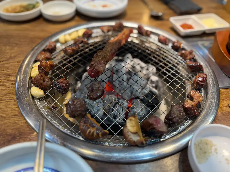 숯불 위에서 지글지글 익어가는 갈비, 육즙이 끓어오르는 모습이 인상적이다.