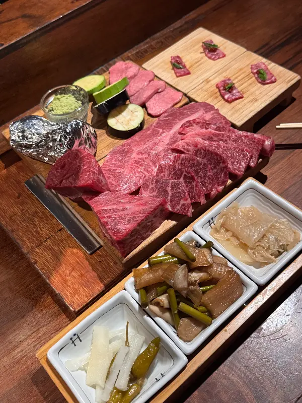 다채로운 한우 부위와 곁들임 찬이 나무 도마 위에 정갈하게 담겨 나온 모습