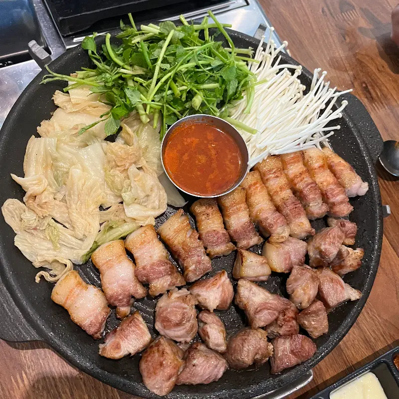 미나리와 팽이버섯이 곁들여진 오대지 식당의 삼겹살 한 상