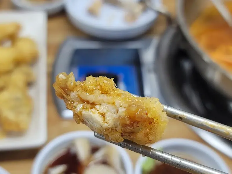 젓가락으로 집어든 복어 튀김 조각의 단면