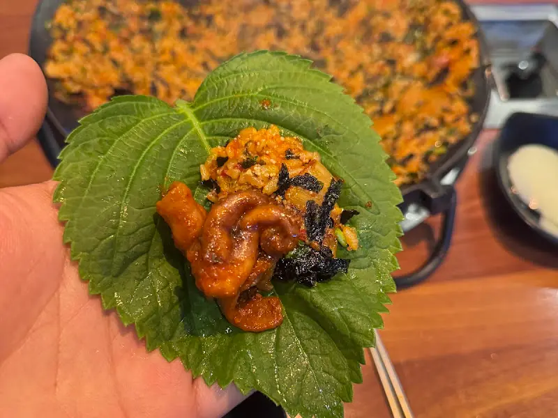 깻잎 위에 쭈꾸미와 볶음밥을 올려 쌈을 싸 먹는 모습