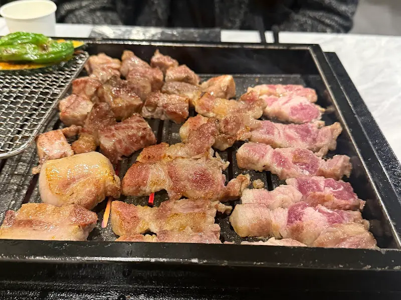 잘 구워진 흑돼지 삼겹살과 목살이 석쇠 위에 올려져 있는 모습