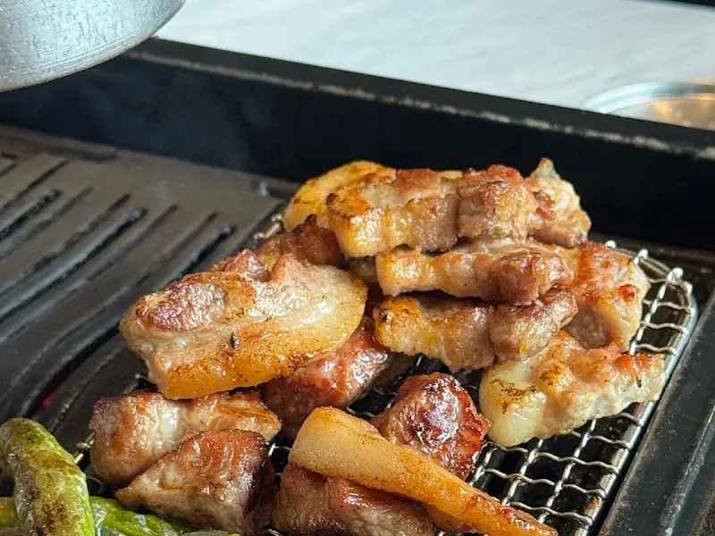 석쇠 위에 잘 구워진 흑돼지 삼겹살과 꽈리고추가 올려져 있는 모습