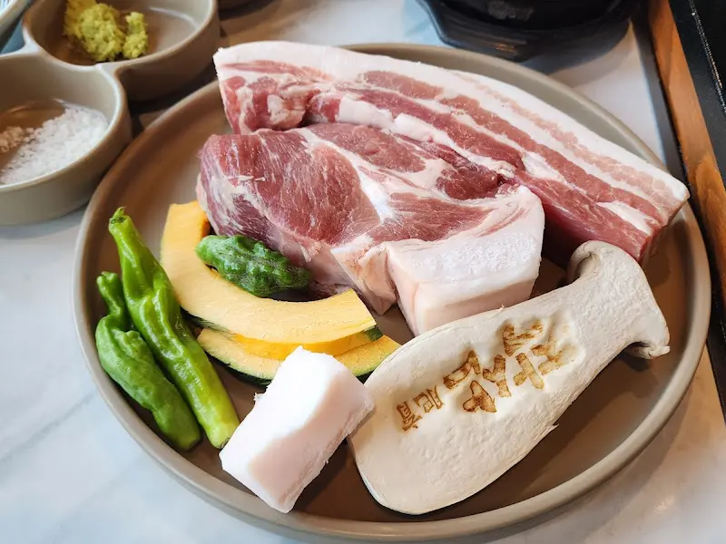흑돼지 삼겹살과 목살, 꽈리고추, 버섯, 호박 등이 담겨져 있는 접시