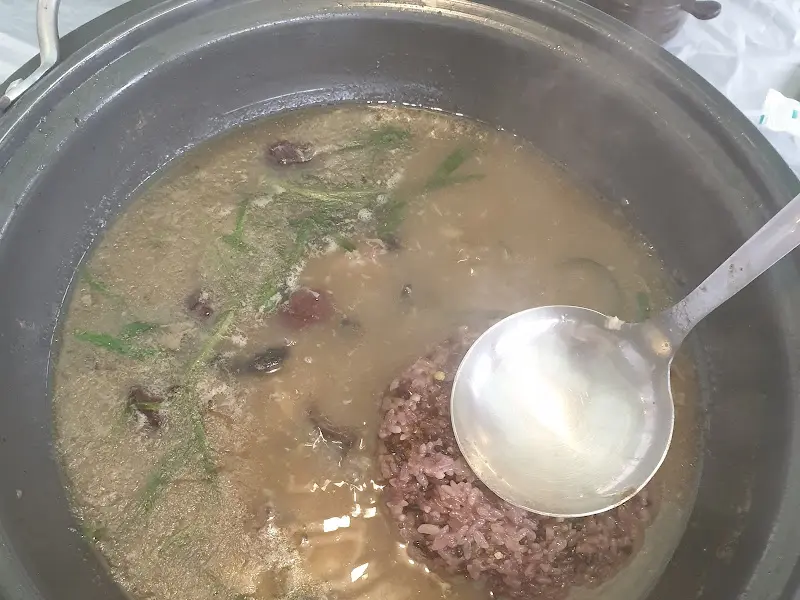 닭죽을 숟가락으로 뜨는 모습