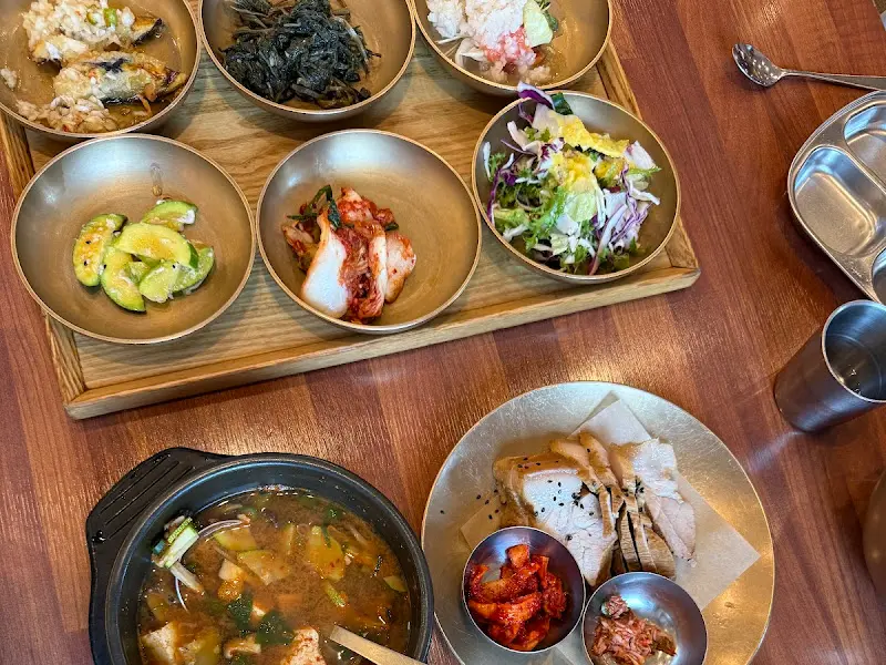 놋그릇에 정갈하게 담긴 다양한 반찬들과 솥밥, 된장찌개