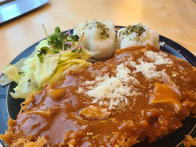 두툼한 흑돼지 돈까스와 샐러드, 밥이 함께 담겨 있는 접시 사진