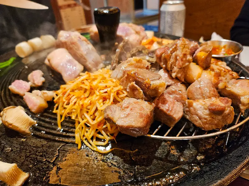 솥뚜껑 위에 올려진 돼지고기와 곁들임 채소