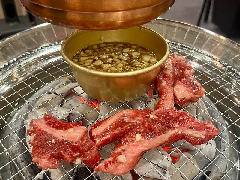 숯불 위에서 익어가는 소갈비살과 특제 소스