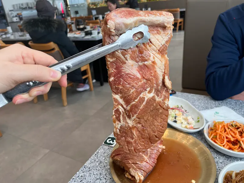 두툼한 돼지갈비를 집게로 들어올린 모습