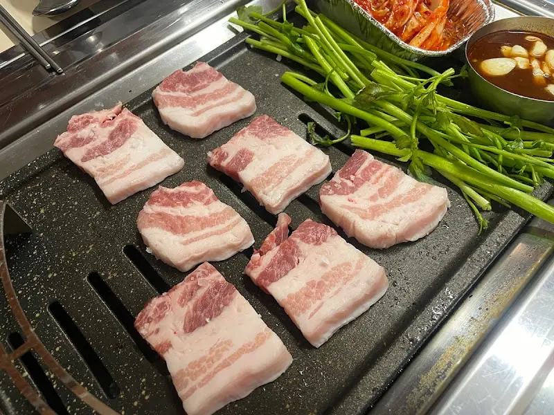 불판 위에 올려진 삼겹살과 미나리