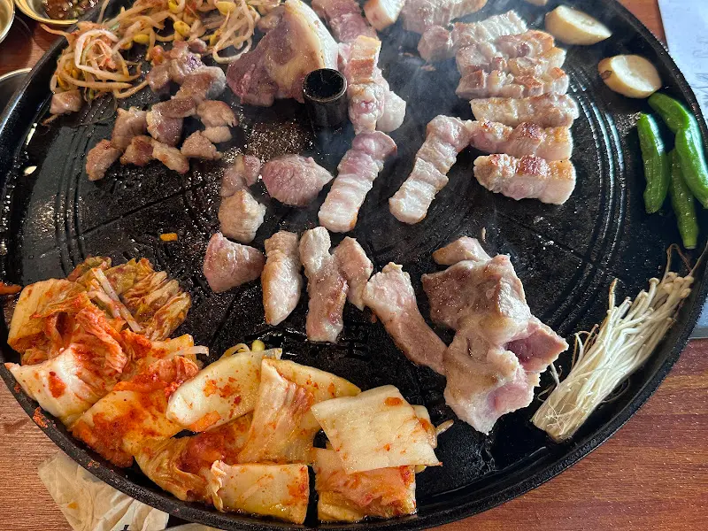 솥뚜껑에 구워진 삼겹살과 김치