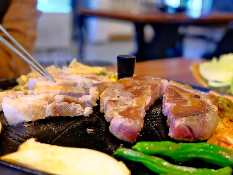 노릇하게 구워진 삼겹살을 쌈에 싸먹는 모습