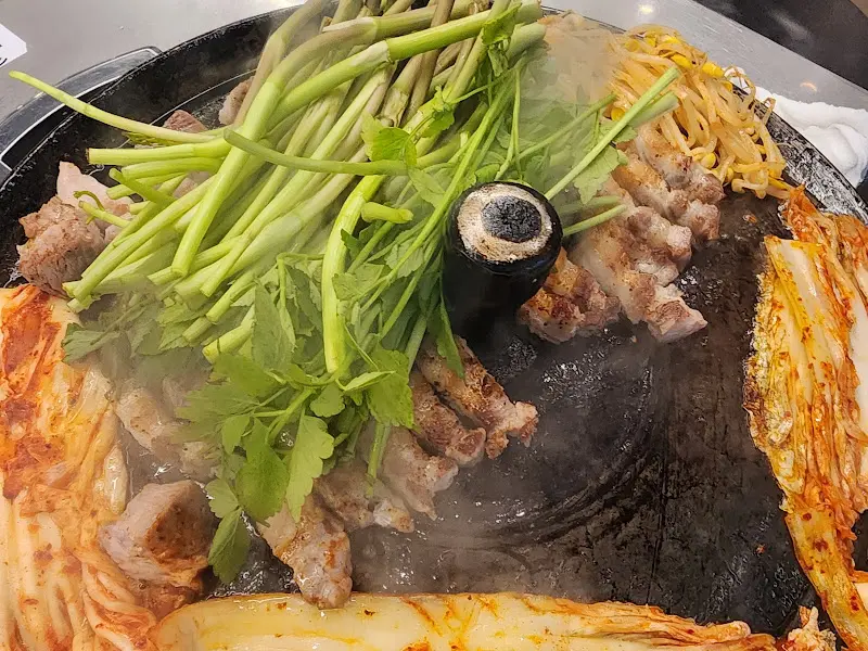 불판 위에서 익어가는 삼겹살과 미나리의 조화