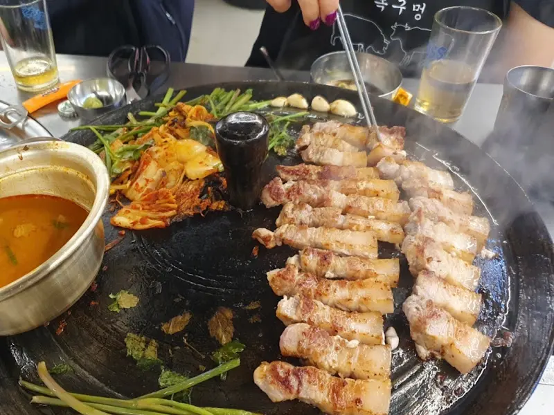 불판 가득 채워진 삼겹살과 다채로운 곁들임