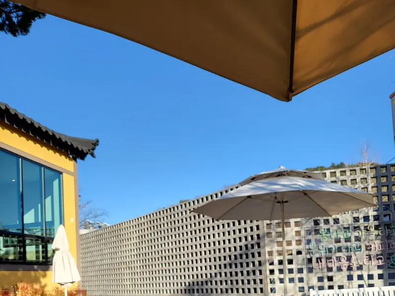 만랩커피 야외 테이블. 파라솔 아래에서 커피를 즐길 수 있도록 테이블과 의자가 마련되어 있다.