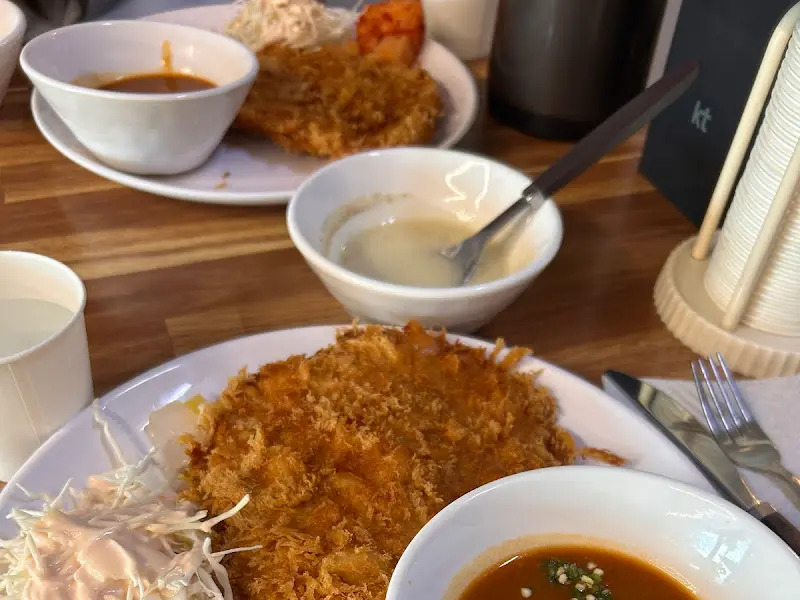 돈까스 두 덩이와 샐러드, 깍두기, 밥이 한 접시에 담겨 있는 모습