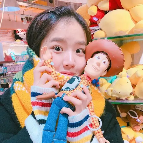 밝은 표정으로 인형을 들고 있는 여성