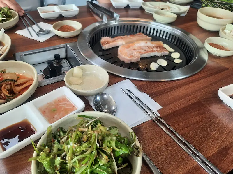 흑돼지 삼겹살과 다양한 반찬이 차려진 테이블