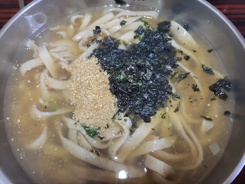 김 가루와 깨가 듬뿍 뿌려진 콧등치기 국수의 클로즈업