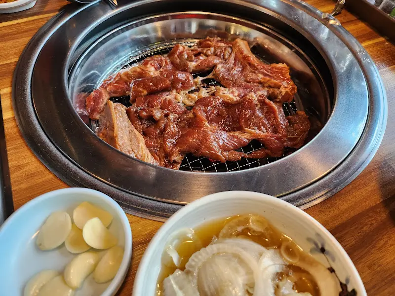 숯불 위에서 노릇하게 익어가는 돼지갈비. 마늘과 양파절임도 함께 구워 먹으면 더욱 맛있다.