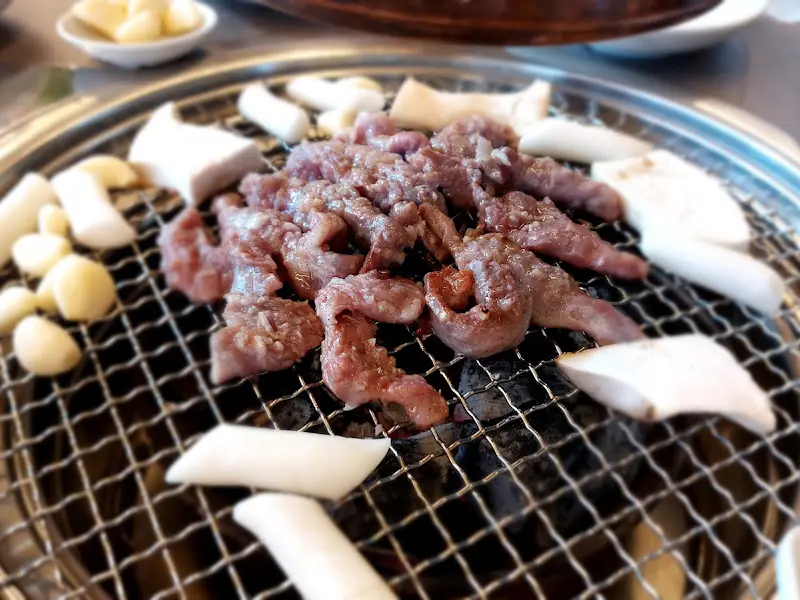 불판 위에서 구워지는 갈매기살, 떡, 마늘