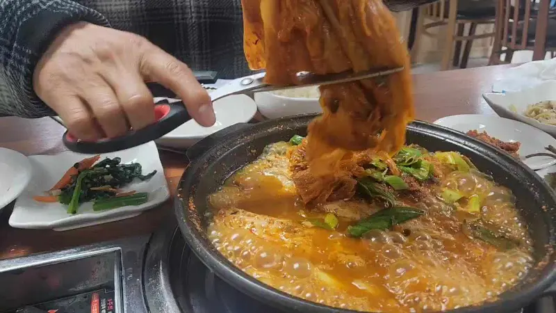 김치찜 속 묵은지를 집게로 들어올려 보여주는 모습