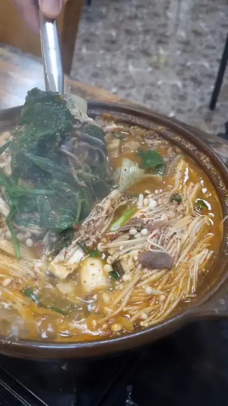 전골 속 흑염소 고기를 집어 올리는 모습