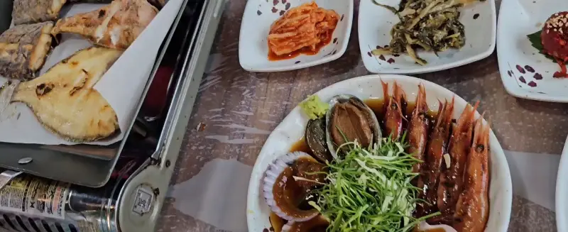 테이블 가득한 반찬과 생선, 새우