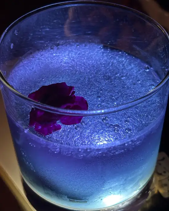 푸른빛 도는 칵테일에 꽃잎이 띄워진 모습