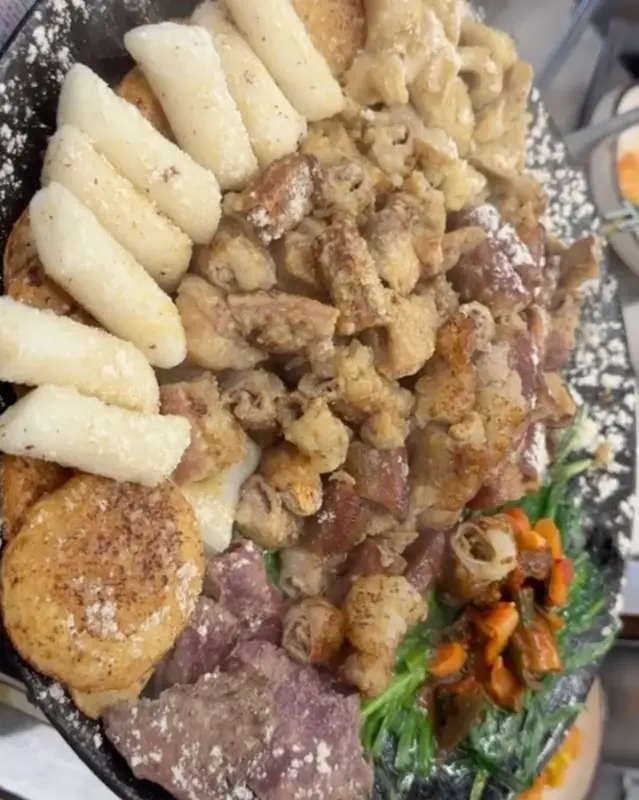 다양한 부위와 떡, 감자가 함께 구워진 마늘 곱창 한 상 차림