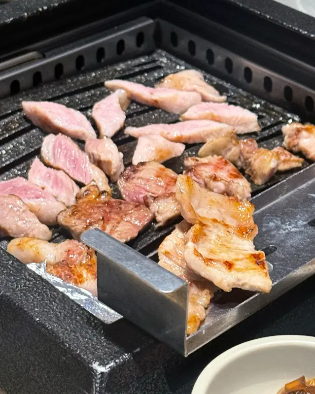 불판 위에서 먹기 좋게 잘린 고기 조각들이 노릇하게 구워지고 있는 모습