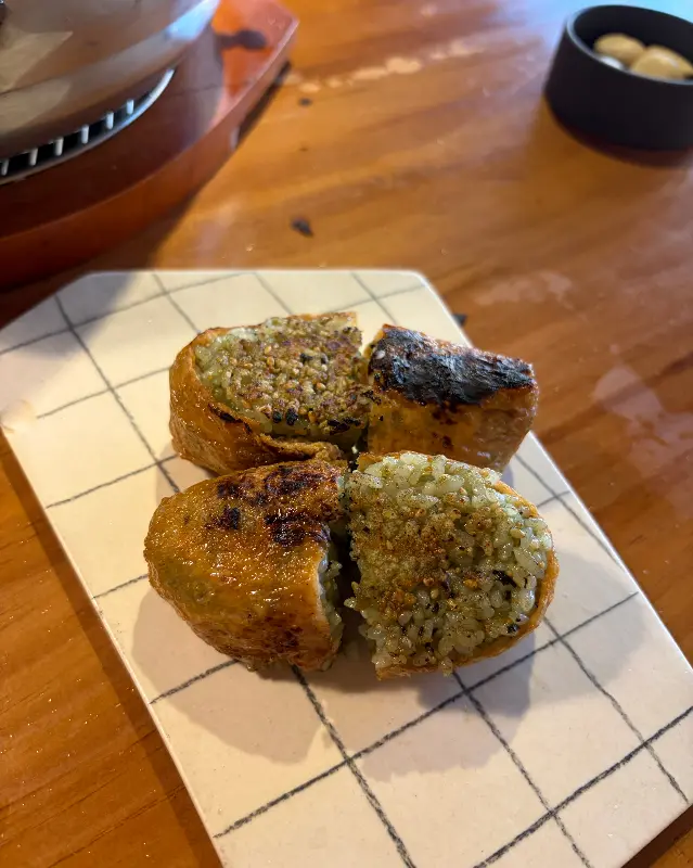 네 조각으로 나뉜 구운 유부초밥이 접시에 담겨있다.