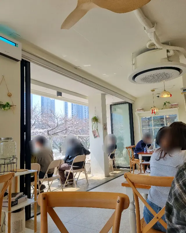 벚꽃이 보이는 창가 좌석에서 식사하는 손님들