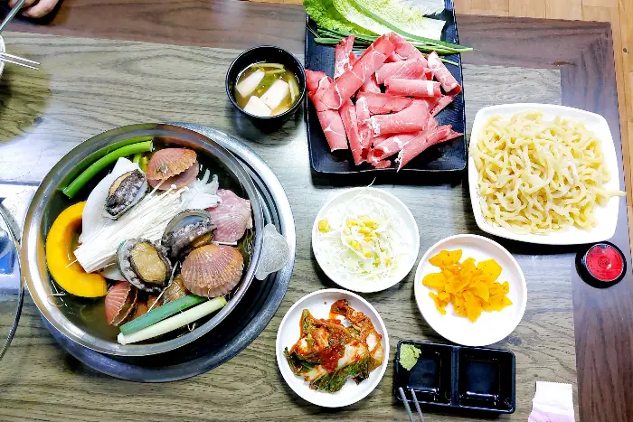 테이블에 차려진 푸짐한 해물 샤브샤브와 곁들임 메뉴
