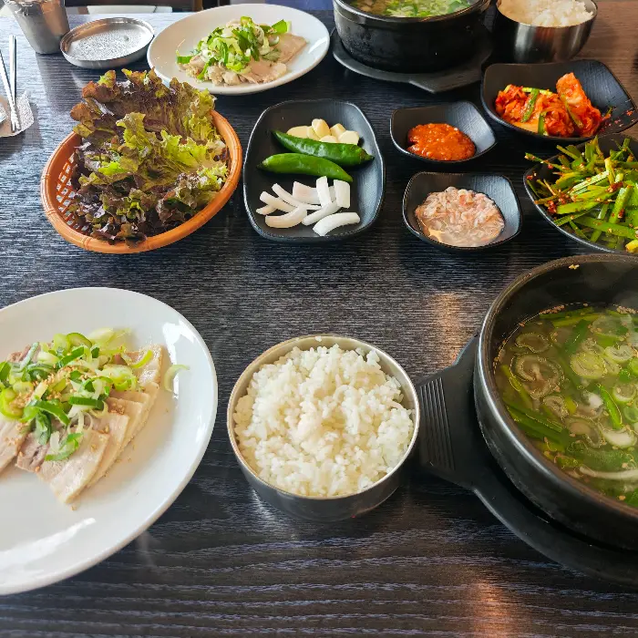 흰 접시에 담긴 부드러운 수육과 곁들임 반찬