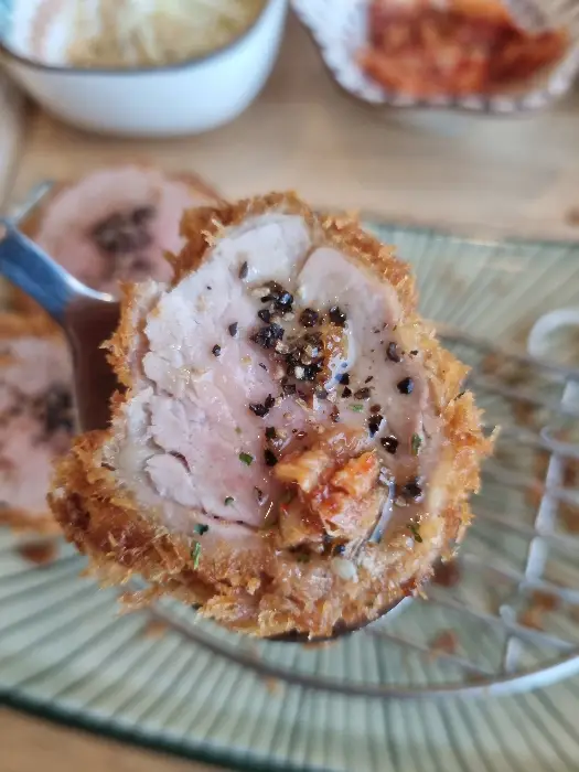 포크 위에 올린 돈까스 단면이 부드럽고 촉촉해 보이는 모습