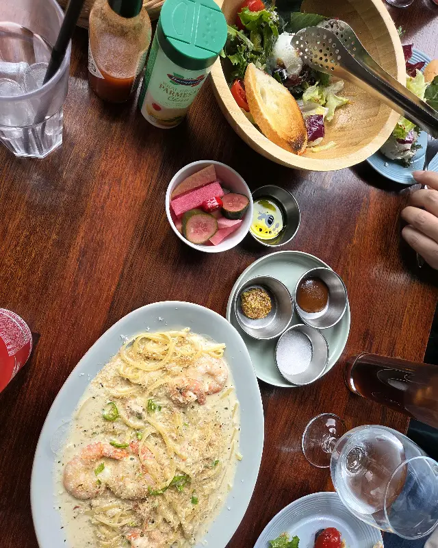 테이블 위에 놓인 파스타, 샐러드, 피클, 소스 등의 모습