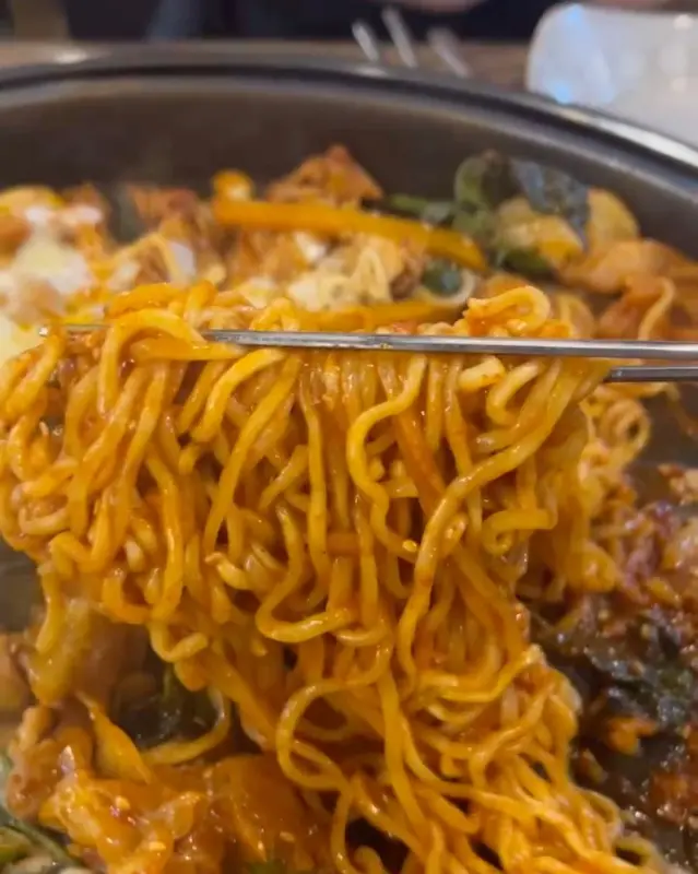 젓가락으로 닭갈비 양념이 잘 배인 우동 면발을 들어올리는 모습