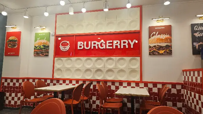 버거리 매장 내부 전경. 붉은색 체크무늬 벽과 'BURGERRY' 로고가 돋보인다.
