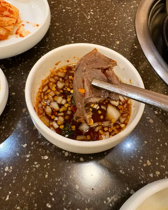 고기 한 점을 간장 소스에 찍어 먹는 모습