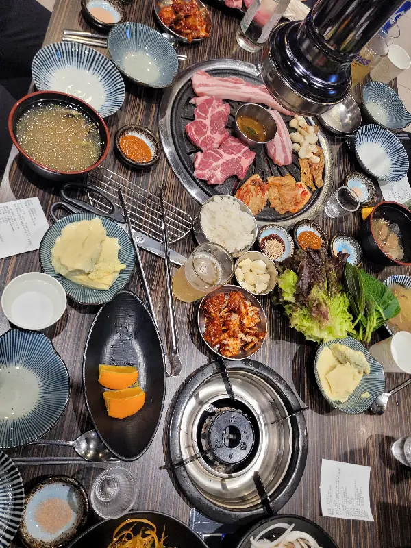 테이블 가득 차려진 밑반찬과 고기의 모습