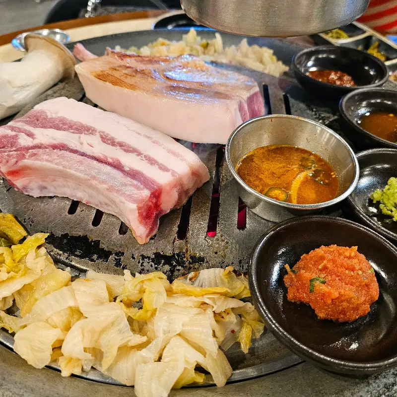 불판 위에 올려진 숙성 삼겹살과 밑반찬들