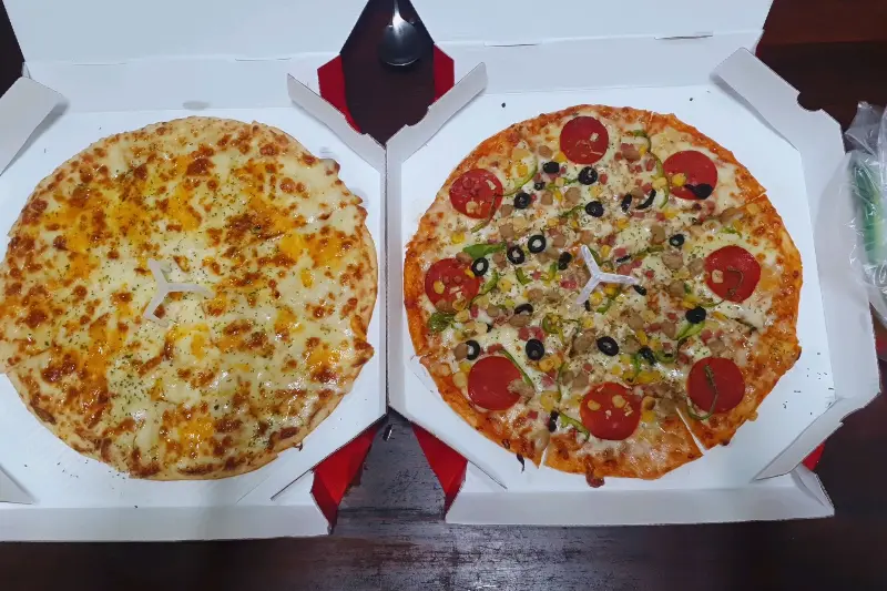 두 판의 피자가 나란히 놓여 있다. 하나는 치즈 피자, 다른 하나는 토핑이 풍성한 피자.