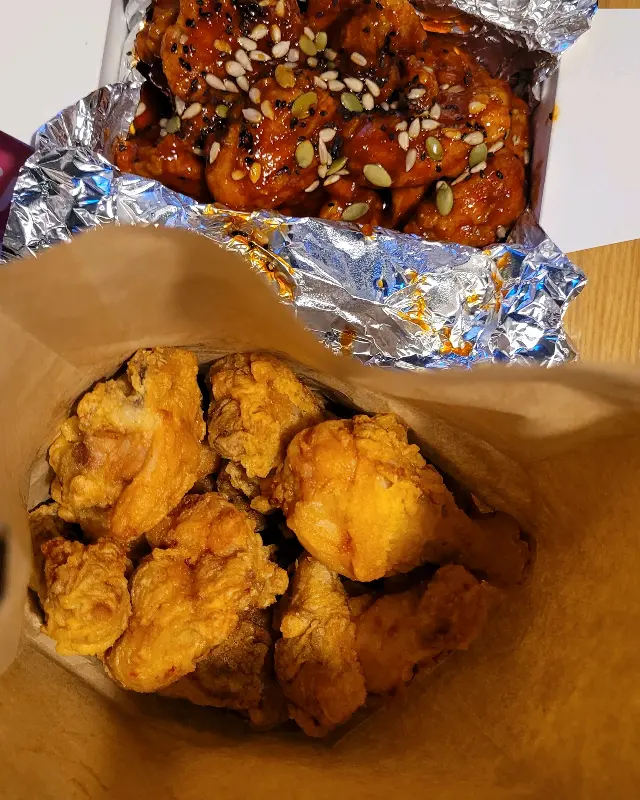 종이 봉투에 담겨 나온 후라이드 치킨과 양념 치킨