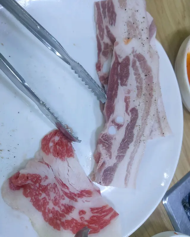 잘 익은 고기를 집게로 들어 올리는 모습