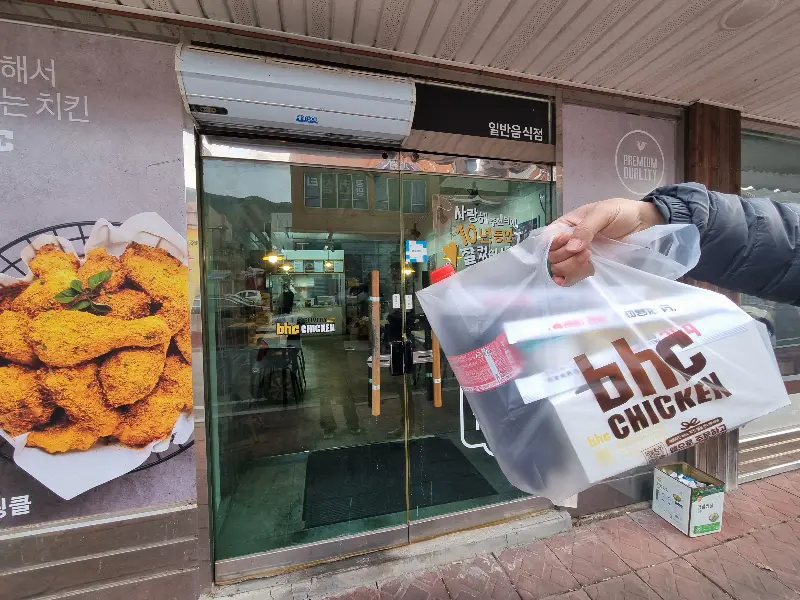 BHC 매장 앞에서 포장된 치킨 봉투를 들고 있는 모습