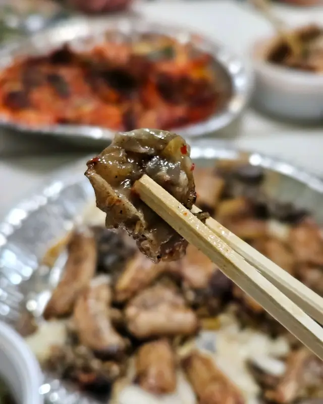 젓가락으로 집어 올린 꼼장어 소금구이